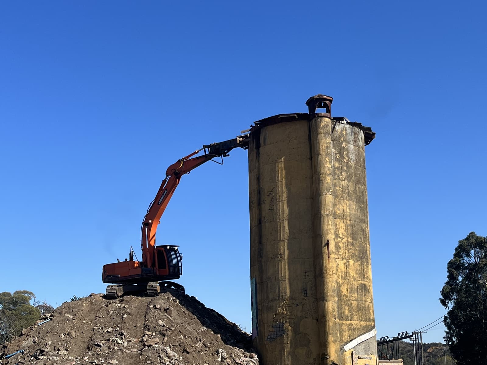 Excavadora con martillo hidráulico demoliendo un silo industrial